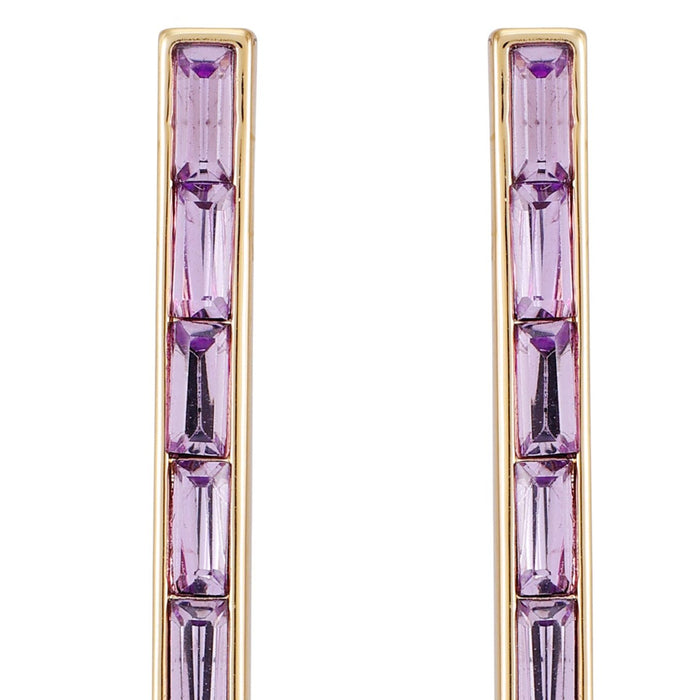 Close-up of the Vince Camuto Goldtone Violet Stone Baguette Stick Drop Earrings, featuring two vertical goldtone bars each adorned with three rectangular faceted violet stones, exemplifying a modern and elegant stick drop design against a white background.