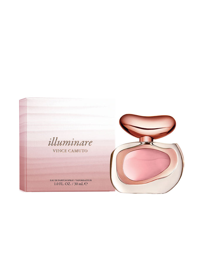 A 1.0 oz bottle of Vince Camuto Illuminare Eau de Parfum, featuring a pink liquid and a distinctive gold and pink cap, is displayed next to its elegant pink gradient box. The luxurious ambery musk fragrance comes in sophisticated packaging, with the box clearly showing the Vince Camuto name and product size.