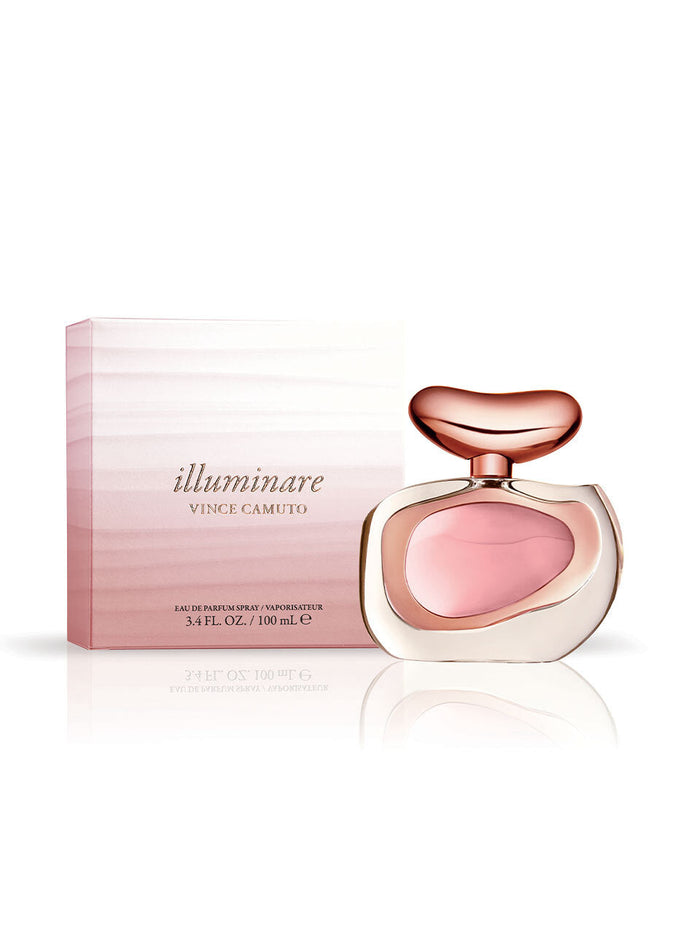 A bottle of Vince Camuto Illuminare 3.4 oz Eau de Parfum, topped with a pink and gold cap, sits in front of its coordinating pink gradient box. The bottle showcases light pink liquid and contains 100 mL, delivering a radiant ambery musk fragrance that lasts beautifully all day.