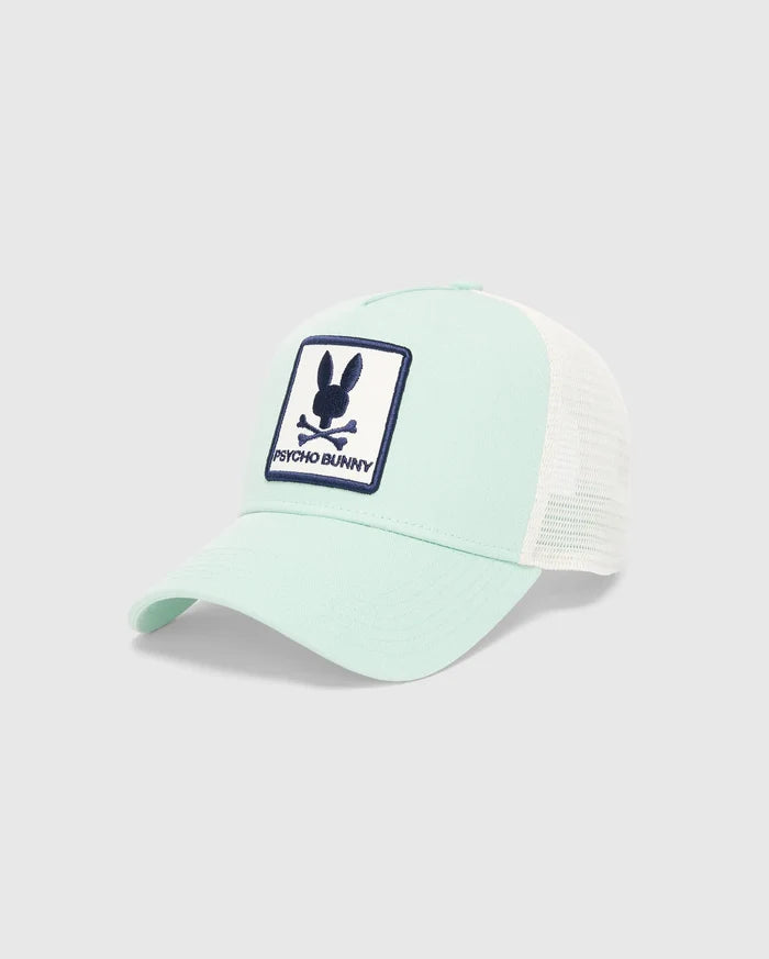 Kids Adamo Bunny Trucker Cap in mint green with white mesh back, featuring a prominent embroidered navy blue and white Psycho Bunny skull logo patch on the front.