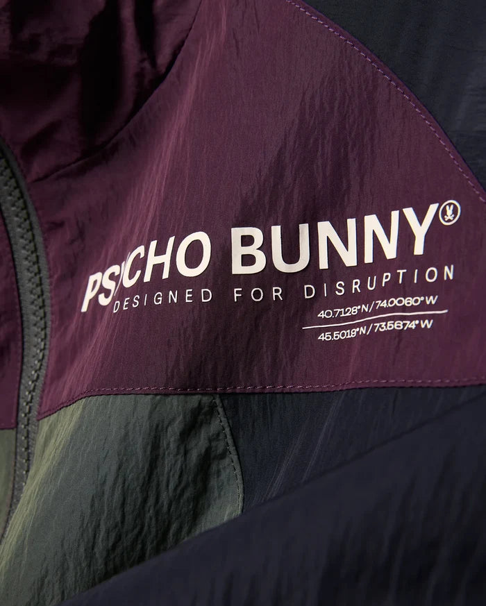 Kids Alder Nylon Colorblock Jacket in plum, olive, and navy, featuring a large white Psycho Bunny logo, Designed For Disruption text, and coordinates on crinkled nylon fabric.