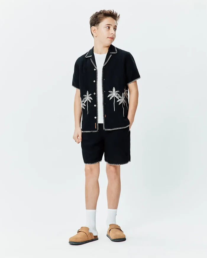 Black short-sleeve button-up shirt with white contrast stitching and palm tree embroidery, paired with matching Black Kids Brad Linen Short featuring white contrast stitching, both in a relaxed fit.