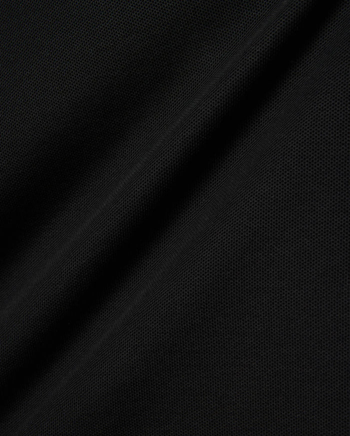 Black Kids Brad Pique Polo fabric, a close-up revealing the refined, breathable textured pique weave with subtle, elegant folds, perfect for premium Psycho Bunny menswear.