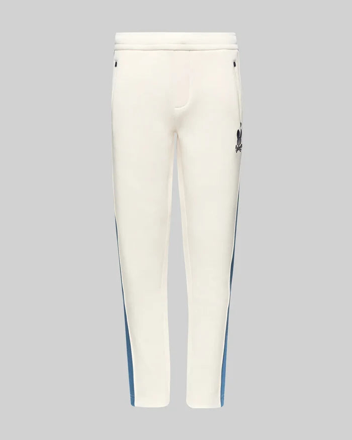 Kids Caspian Contrast Stripe Track Pant in cream, featuring a blue side stripe, relaxed fit, smooth fabric, and a small black embroidered Psycho Bunny skull logo on the upper right thigh.