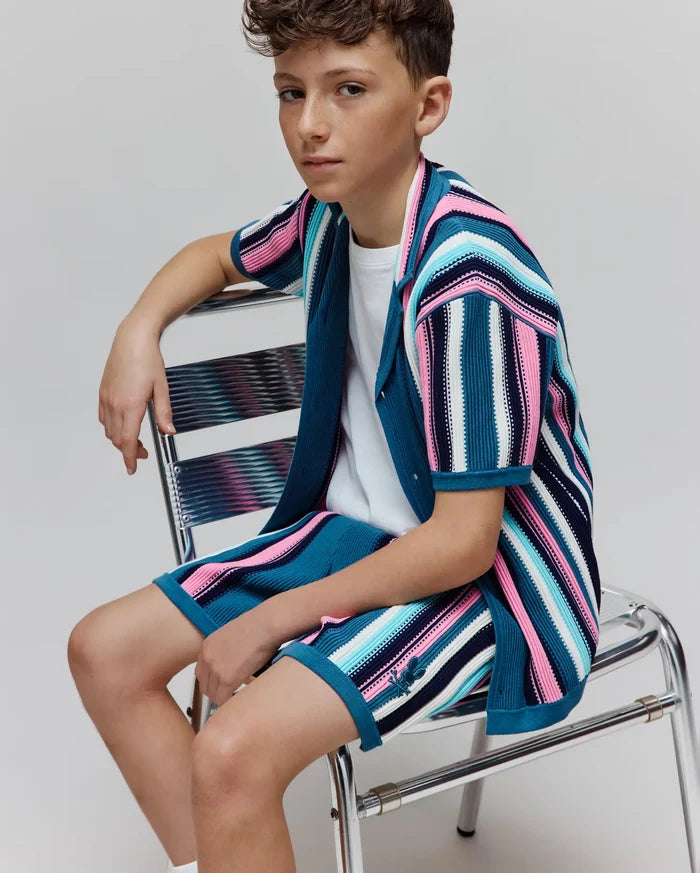 Kids Cliff Knit Shirt and matching shorts, featuring a relaxed fit in a vibrant striped knit of teal, pink, white, and navy, with a small embroidered Psycho Bunny skull logo on the shorts.