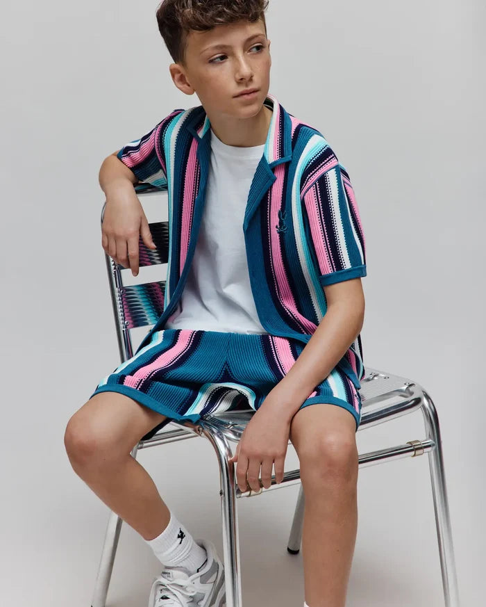 Kids Cliff Knit Short and matching collared shirt in a relaxed fit, featuring bold teal, pink, white, and navy vertical stripes with a ribbed knit texture and small embroidered Psycho Bunny skull logo on the left chest.