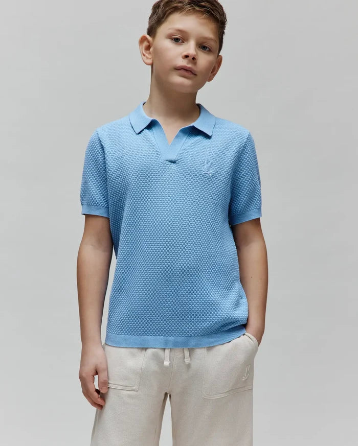 Kids Devon Bubble Stitch Knit Polo in light blue, a classic fit with an open V-neck collar, ribbed cuffs, and a small embroidered Psycho Bunny skull logo on the left chest.