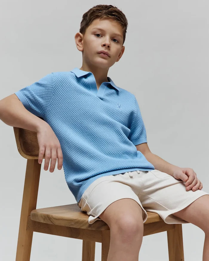 Kids Devon Bubble Stitch Knit Polo in light blue, featuring a textured bubble stitch knit fabric, classic fit, and a small embroidered Psycho Bunny skull logo on the left chest.