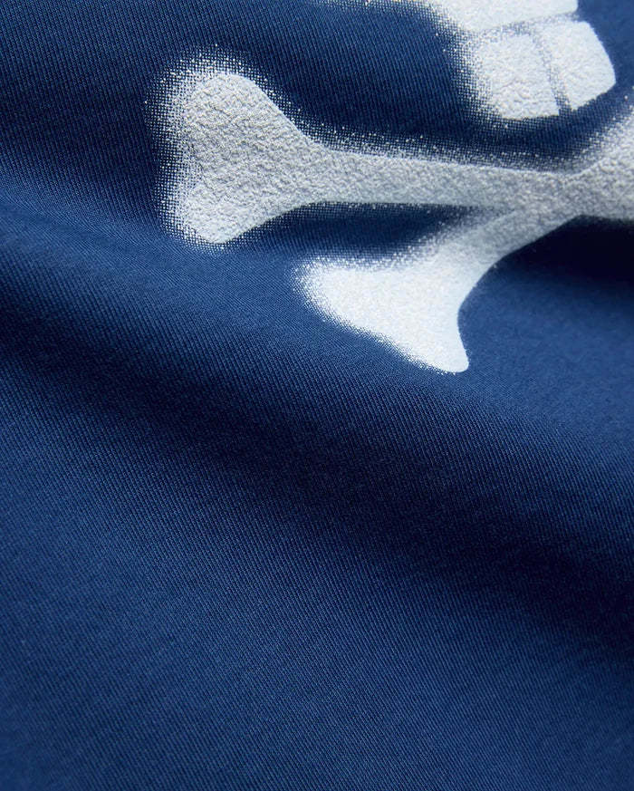 Kids Emmanuel Graphic Tee in deep navy jersey knit, featuring a large, distressed white graphic of a bone, part of the iconic Psycho Bunny skull and crossbones logo.