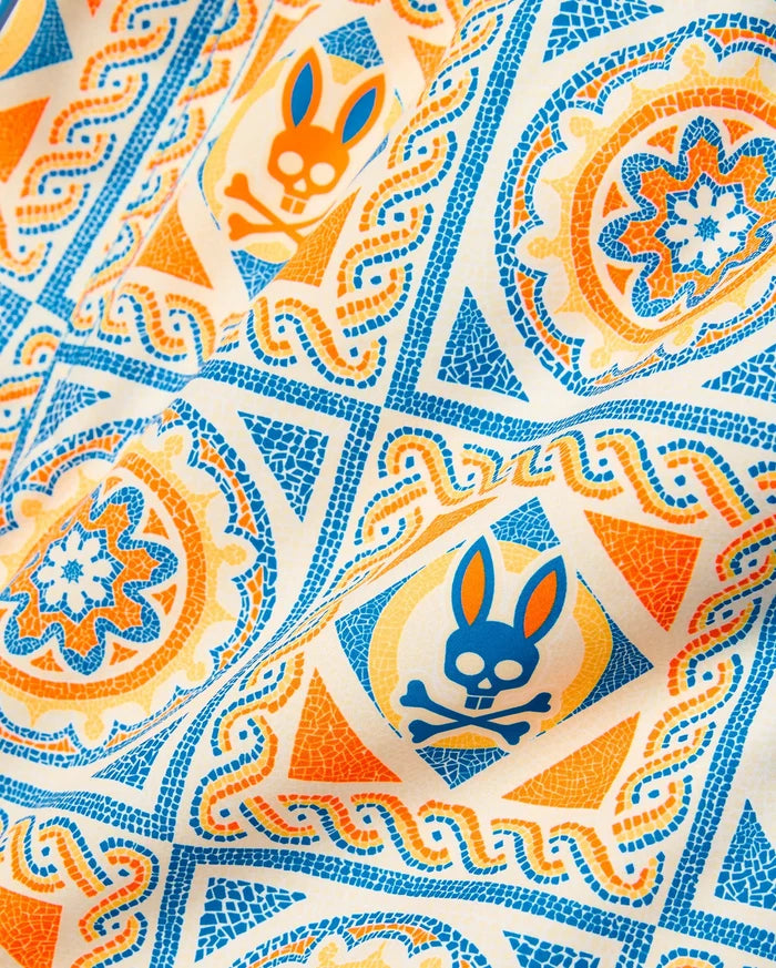 Kids Frank Swim Trunk in an off-white base with a vibrant blue and orange mosaic-style all-over print, featuring geometric shapes, floral motifs, and the iconic Psycho Bunny skull logo.