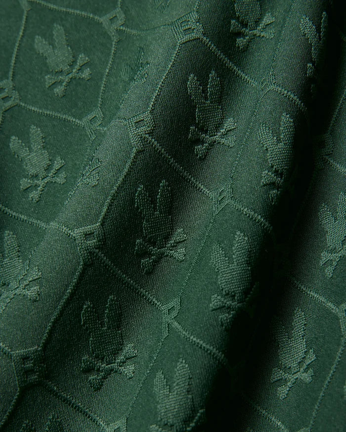 Kids Garry Jacquard Johnny Collar Polo in deep green, featuring an all-over tonal jacquard knit pattern of the iconic Psycho Bunny skull logo within a subtle geometric grid.