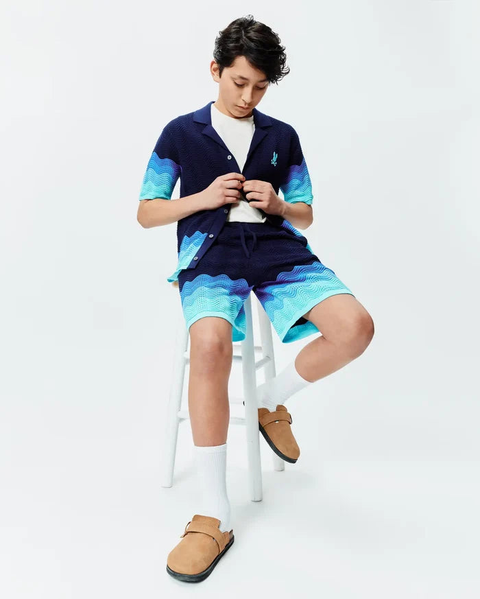 Navy blue knit short-sleeve shirt and Kids Holden Knit Short set featuring a wavy blue gradient pattern, with a small embroidered Psycho Bunny skull logo on the shirt's left chest.