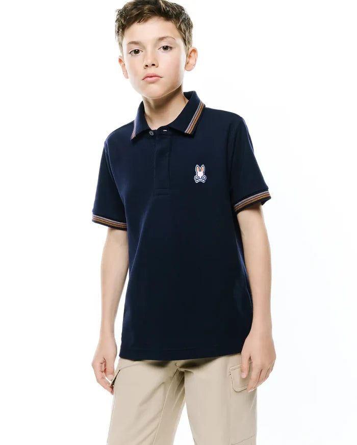Kids Jaydon Pique Polo, a navy classic fit pique polo with orange, white, and brown striped collar and sleeve cuffs, featuring an embroidered Psycho Bunny skull logo on the left chest.