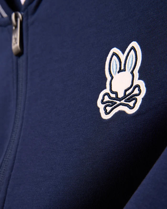 Kids Jaydon Track Jacket in navy blue, featuring a smooth knit fabric and a prominent embroidered white and light blue Psycho Bunny skull logo on the left chest, with a metallic zipper pull.