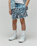 Kids Josh Swim Trunk, white with a deep blue pixelated pattern of repeating Psycho Bunny skull logos, a prominent red bunny logo on the right leg, and a relaxed fit in quick-dry fabric.