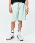 Kids Keith Short in light mint green pique knit, featuring a relaxed fit, drawstring waist with black tips, and a small embroidered Psycho Bunny skull logo on the lower left leg.
