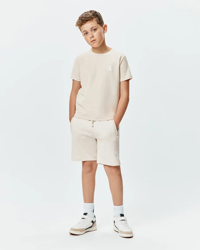 Psycho Bunny kids beige jersey t-shirt and Kids Keith Short 3 1/2 French terry shorts. Both feature white embroidered bunny skull logos, on the left chest and left thigh.