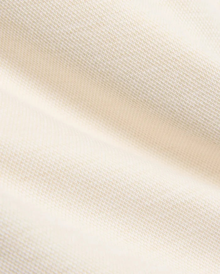 Creamy off-white pique knit fabric for the Kids Keith Short 3 1/2 7 3/4, featuring a finely textured, breathable weave with gentle folds, embodying the premium quality of Psycho Bunny apparel.
