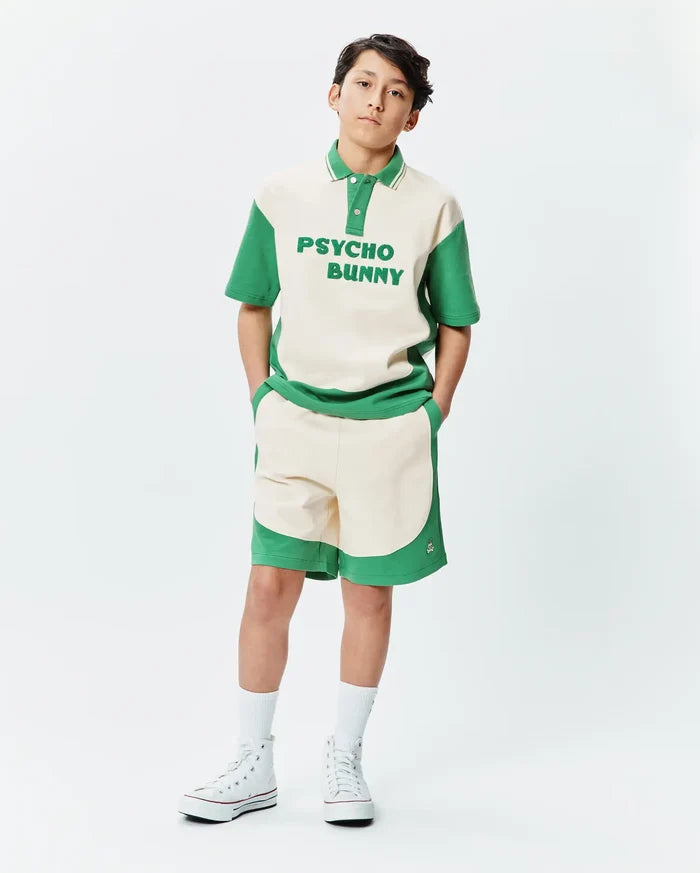 Premium Psycho Bunny cream and green color block polo shirt with bold chest text, paired with matching soft knit Kids Kelly Short featuring a subtle embroidered bunny skull logo.