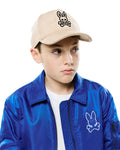 Beige suede Kids Kenneth A-Frame Trucker Cap with a black embroidered Psycho Bunny logo on the front, and a vibrant royal blue satin bomber jacket featuring a large white embroidered Psycho Bunny logo on the left chest.
