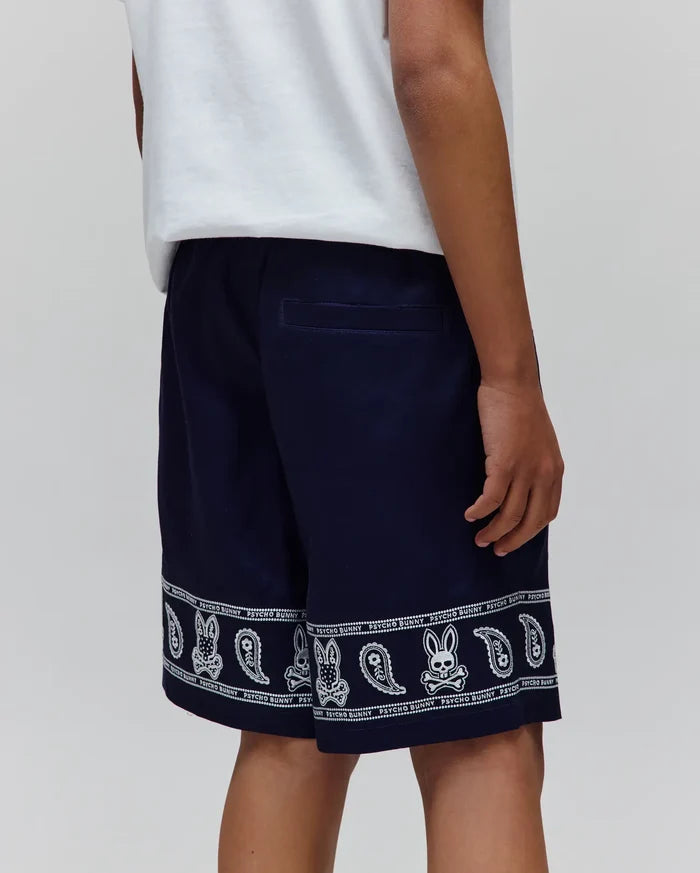 Kids Luke Tencel Short in navy, featuring a relaxed fit and a white bandana-style print along the hem with repeated Psycho Bunny skull logos and paisley patterns.