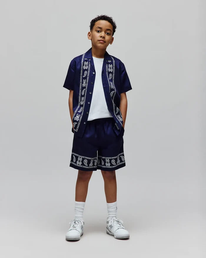 Navy blue Kids Luke Tencel Short and matching relaxed-fit short-sleeve button-up shirt, both featuring a white Psycho Bunny skull and paisley pattern with brand text along the shirt's placket and collar, and the shorts' hem.
