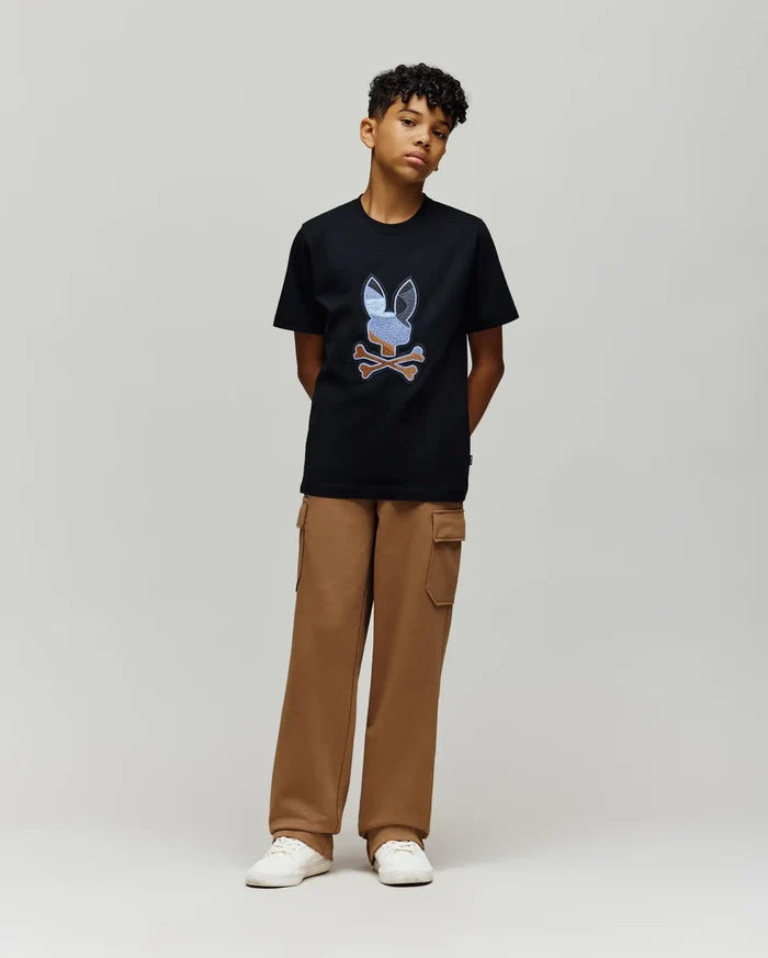 Black jersey t-shirt with a large, multi-color embroidered Psycho Bunny skull logo on the chest, paired with relaxed fit brown French terry Kids Nash Cargo Sweatpant featuring side cargo pockets.