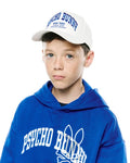 Royal blue relaxed hoodie with large white embroidered Psycho Bunny skull logo on chest, and a white Kids Nathaniel A-Frame Trucker Cap with blue embroidered Psycho Bunny New York text.
