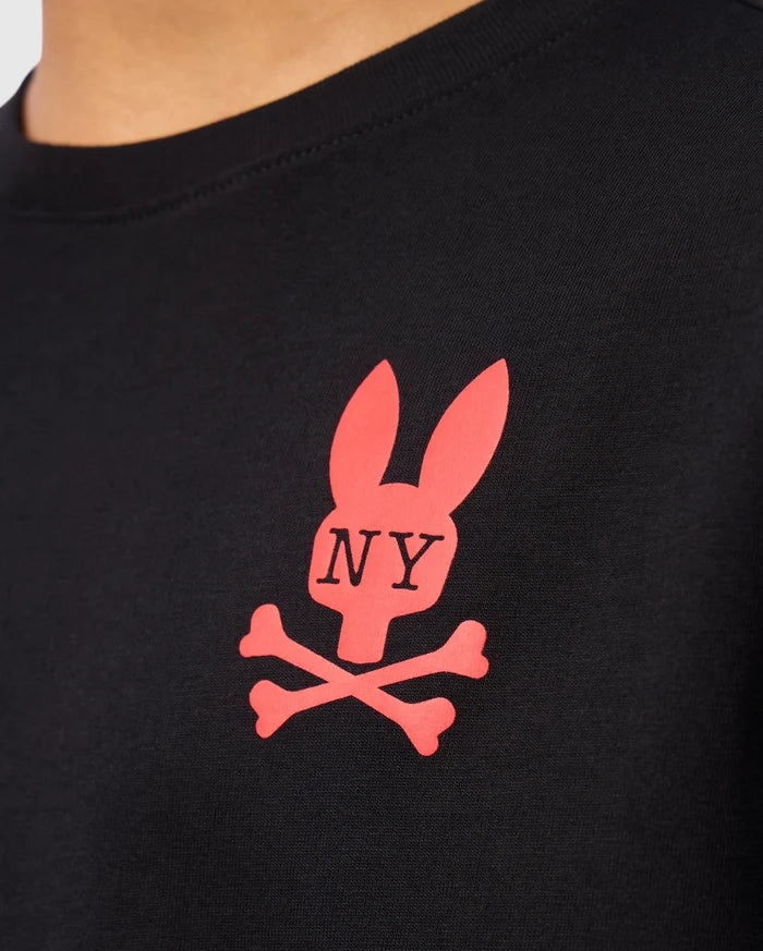 Close-up of a black Psycho Bunny KIDS NEW YORK CITY TEE - B0U554W1PC, crafted from premium Pima cotton and featuring a red logo with a stylized rabbit head above crossed bones. The letters "NY" are printed on the rabbit's face, making this tee both stylish and comfortable for kids.