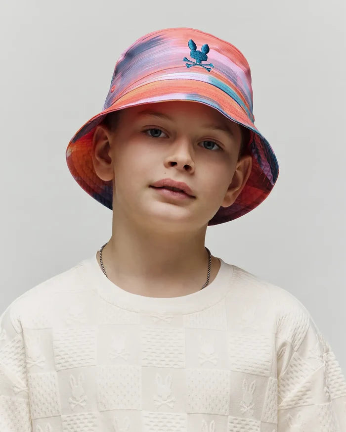 Kids Raphael Bucket Hat in vibrant multi-color tie-dye with a small teal embroidered Psycho Bunny logo, paired with an off-white textured long-sleeve crewneck featuring an all-over embossed checkerboard Psycho Bunny pattern.