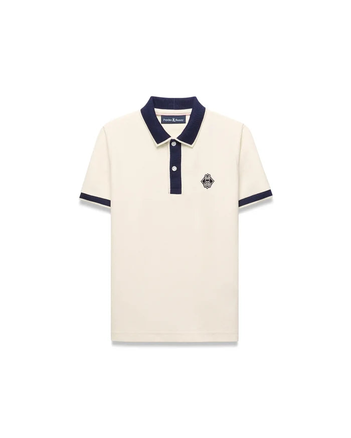 Kids Robin Pique Polo in cream pique fabric with a navy blue collar, placket, and sleeve cuffs, featuring a classic fit and an embroidered Psycho Bunny skull logo on the left chest.