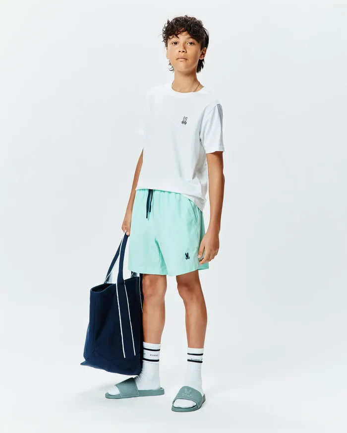 White classic fit jersey t-shirt with small embroidered Psycho Bunny logo, Kids Samos Hydrochromic Printed Swim Trunk in mint green with navy drawstring and embroidered logo, white crew socks with black stripes and Psycho text, and teal slides with embossed logo.