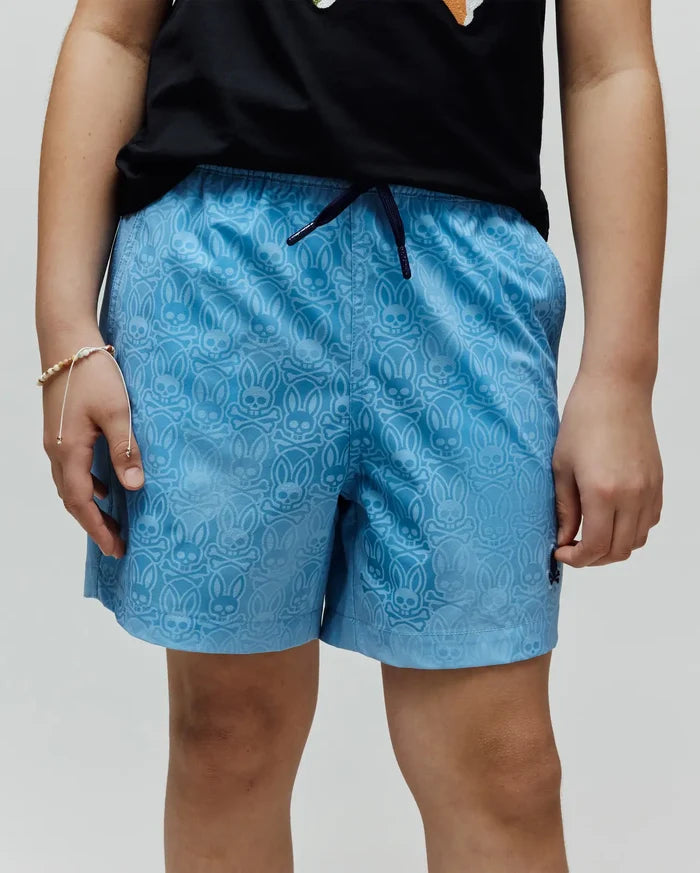 Kids Samos Hydrochromic Printed Swim Trunk, light blue with an all-over tonal Psycho Bunny skull and crossbones pattern, dark blue drawstring, and small embroidered logo on the left leg.