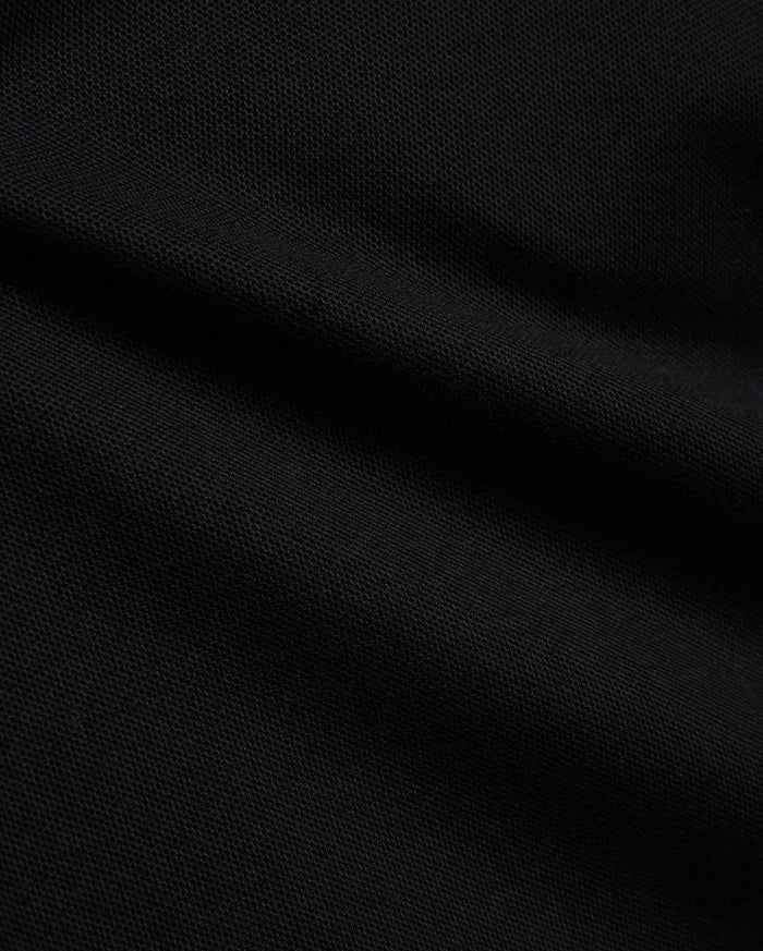 Psycho Bunny Kids Stan Pique Polo in deep black, showcasing the premium, breathable pique knit fabric with a subtle texture, perfect for refined streetwear.