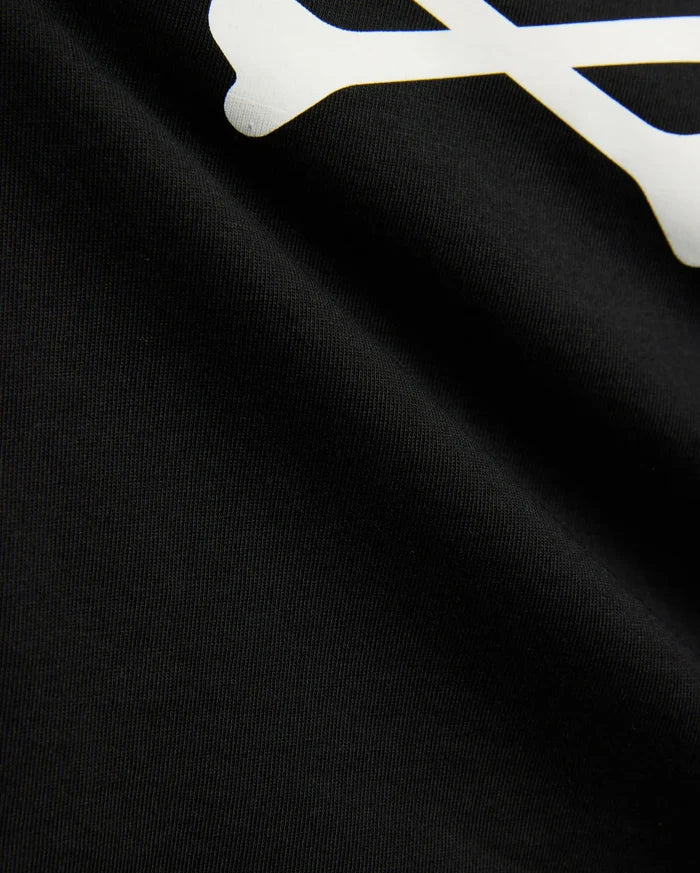 Kids Sunny Graphic Tee in black jersey knit, showcasing a large white graphic print of a bone, a key element of the iconic Psycho Bunny skull and crossbones logo.