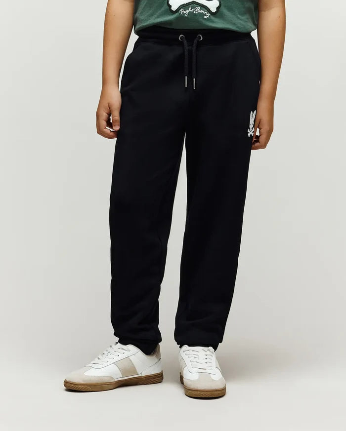 Kids Tate Chenille Sweatpant in black french terry, featuring a relaxed fit, drawstring waist, and a white chenille Psycho Bunny skull logo on the right thigh.