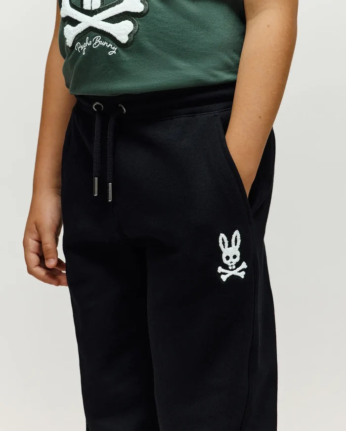 Kids Tate Chenille Sweatpant, black relaxed fit French terry sweatpants with drawstring waist, silver aglets, and a white chenille embroidered Psycho Bunny skull logo on left thigh.