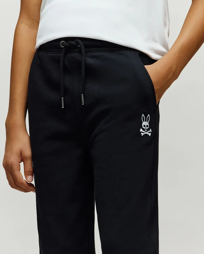 Kids Timothy 4k Bunny Jogger in black french terry, featuring a relaxed fit, drawstring waist with silver tips, and a small white embroidered Psycho Bunny skull logo on the left thigh.