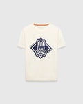 Kids Tobias Graphic Tee, a classic fit cream jersey t-shirt with a large, textured navy blue Psycho Bunny skull and crossbones logo graphic inside a diamond on the chest, featuring orange neckline trim.