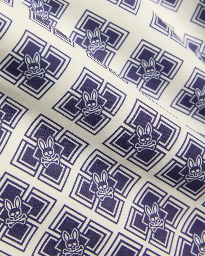 Kids Tobias Swim Trunk in cream with an all-over navy blue geometric square pattern featuring repeated Psycho Bunny skull logos on smooth woven fabric.