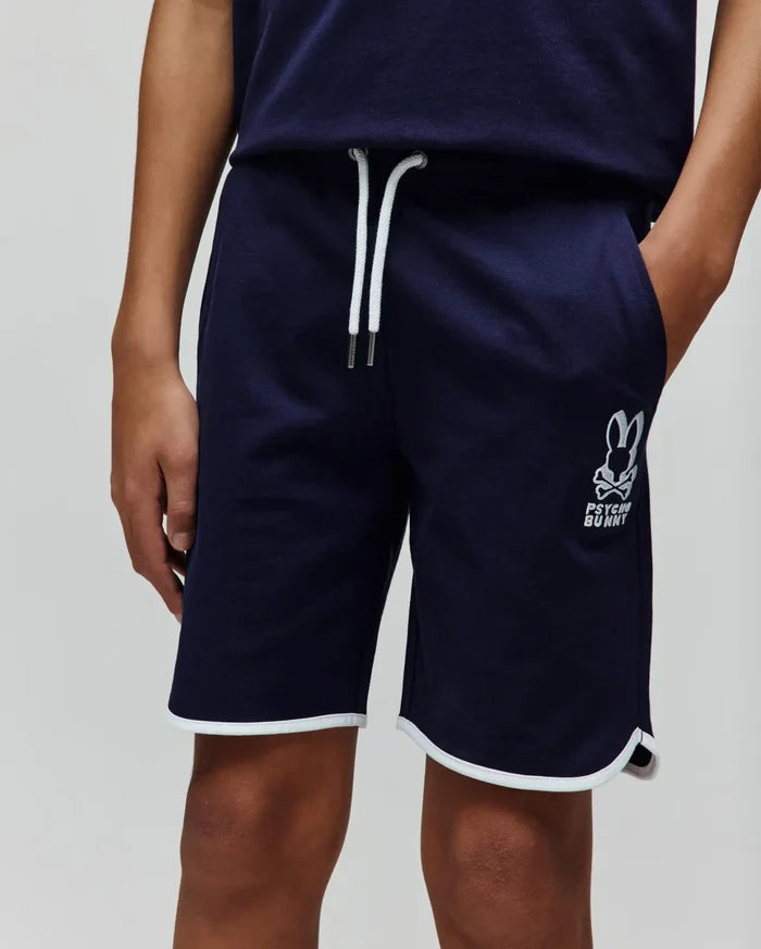 Kids Toby Short, navy French terry shorts with a relaxed fit, featuring white drawstrings, a large embroidered Psycho Bunny skull logo on the left leg, and white piping on the curved hem.