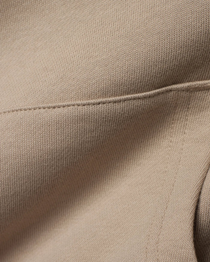 Kids Ty French Terry Hoodie crafted from luxurious, soft beige French terry knit fabric, featuring a meticulously stitched seam detail that highlights the garment's refined construction.
