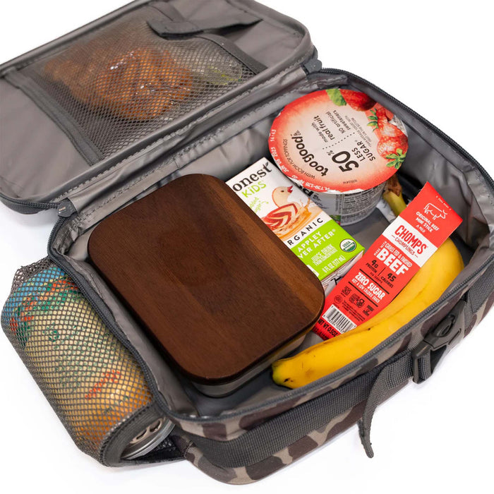 Burlebo lunchbox filled with a wooden bento box, banana, Honest juice box, yogurt, and beef stick. Mesh pouch on the lid holds a snack and drink can.