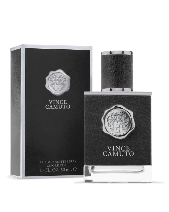 A 1.7 oz bottle and box of Vince Camuto Men’s Eau de Toilette Spray, both in black with silver accents, feature the Vince Camuto crest and brand name on the front. This masculine fragrance is characterized by notes of rich musk.