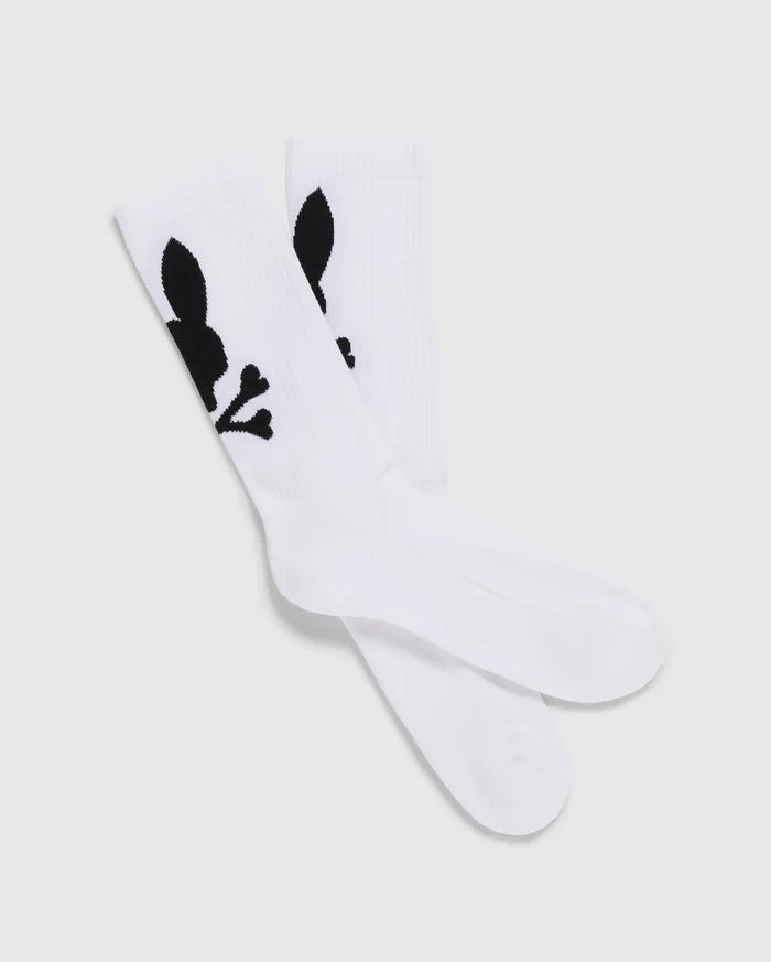 A pack of 3 Men's Sport Socks (B6F997D200) by Psycho Bunny, crafted from luxurious Peruvian Pima cotton in white, features a distinctive black graphic design of a skull with bunny ears and bones. The socks are displayed with one pair slightly overlapping the other on a plain, light-colored background.