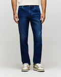 Mens Ace Knit Denim Pant in dark blue knit denim with subtle fading, a classic fit, and a small orange Psycho Bunny tag on the coin pocket.