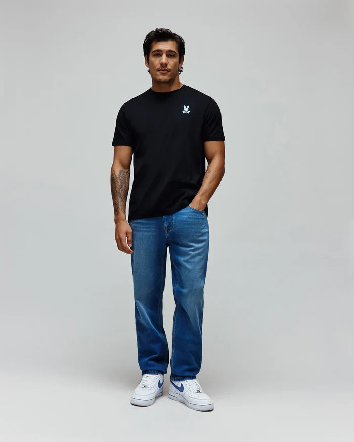 Black classic fit jersey t-shirt with a small embroidered light blue Psycho Bunny skull logo on the left chest, paired with relaxed fit medium blue washed MENS ACE KNIT DENIM PANT.