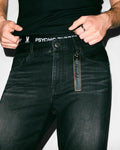 Black Mens Ace Knit Denim Pant, slim fit, with a subtle distressed texture and an attached brown leather Psycho Bunny embossed keychain. Black ribbed undershirt and black Psycho Bunny logo waistband underwear.