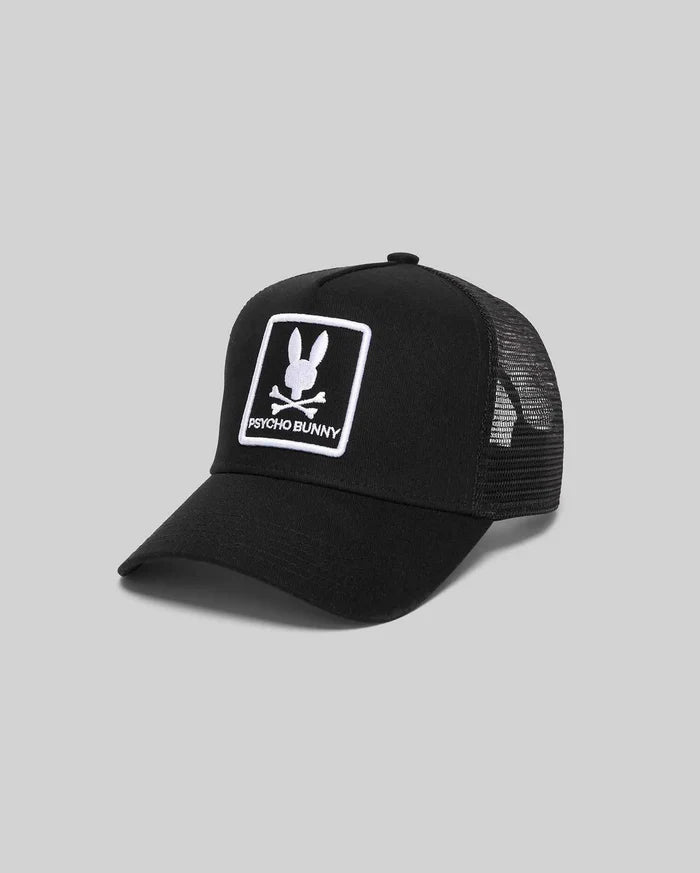 Black Mens Adamo Trucker Cap with a cotton twill front and breathable mesh back. Features a prominent white embroidered Psycho Bunny skull logo patch on the front crown.
