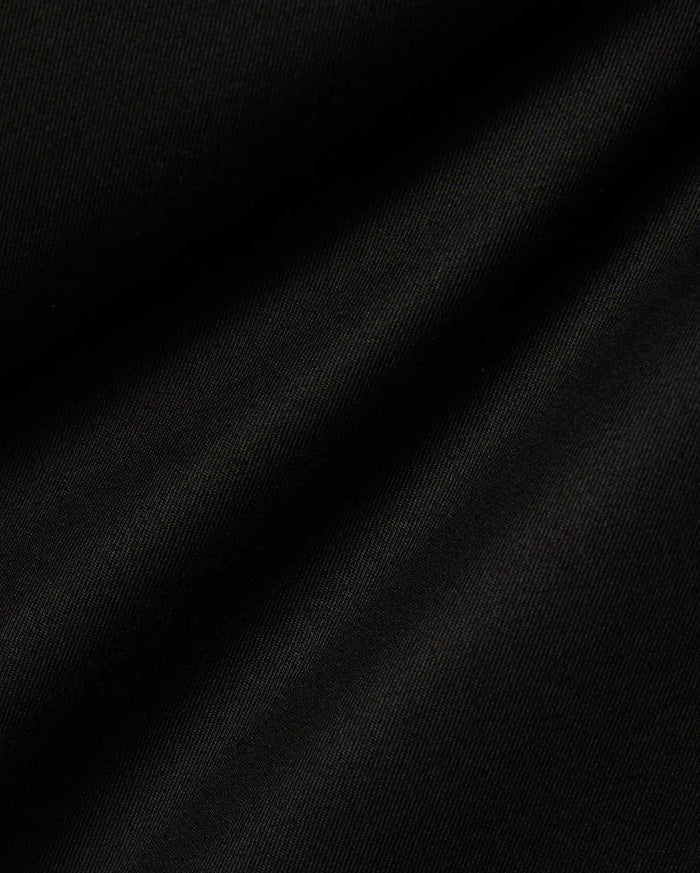 Mens Aidan Chino Pant in deep black, featuring a finely woven twill fabric with distinct diagonal ridges, creating a smooth texture and soft, undulating folds that suggest a comfortable drape.